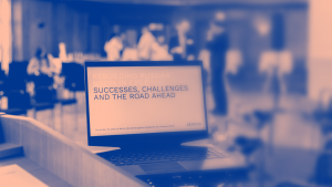 Ein Computerbildschirm in einem Konferenzsaal trägt die Aufschrift: "Successes, challenges and the road ahead". © JX Fund