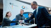 Der deutsche Bundeskanzler Friedrich Merz schüttelt Olena Vysokolian von Suspilne die Hand am Stand der DW Akademie beim Café Kyiv 2026.